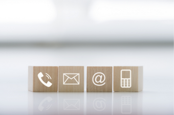 four wooden blocks with icons from left to right, a phone, an email, an at symbol and a cell phone