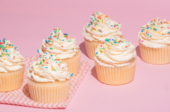 vanilla cupcakes with frosting and sprinkles on a table